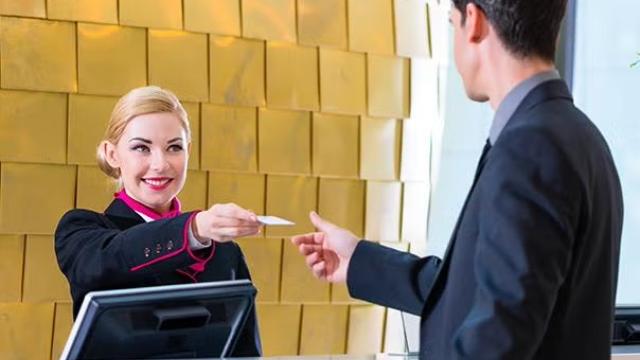 Hotel staff handing over keycard to guest demonstrating how Corporate Traveller makes the job of designing a travel policy easy with its unique automated online travel policy tool