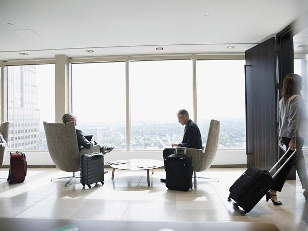 Males and female in lounge with carry-on suitcases