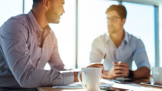 Two males having coffee and discussing business travel expenses