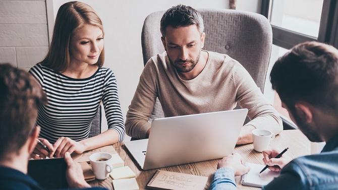 Group of people meeting and reading a travel expense policy off a laptop