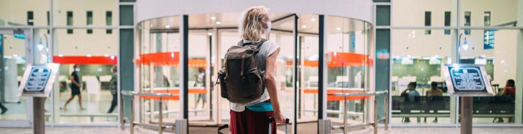 Blonde woman with suitcase outside departures terminal