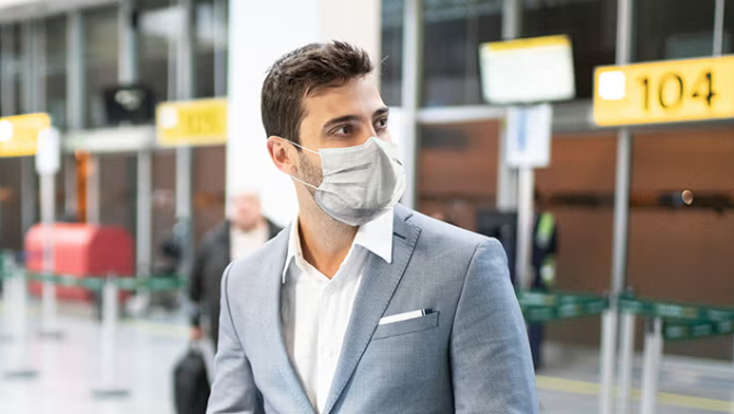 Man walking in the airport holding a tablet representing the pros and cons of unmanaged travel versus a managed travel