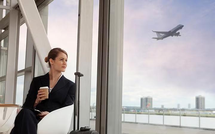 A woman looking at an airplane while sitting in the airport demonstrating how to leverage corporate travel discounts to maximise your savings.