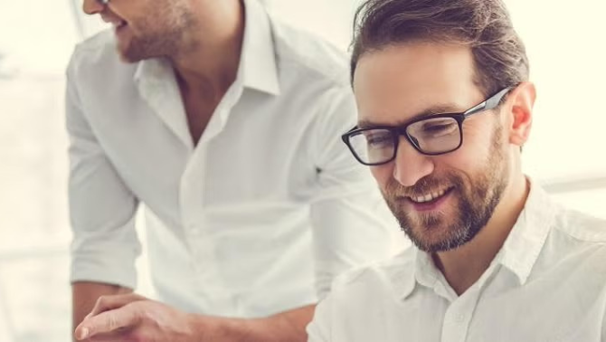 A man wearing eye glasses at work representing essential planning tips for business travel.