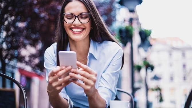 Woman smiling looking at smartphone demonstrating how expert help can reduce the stress of business travel.