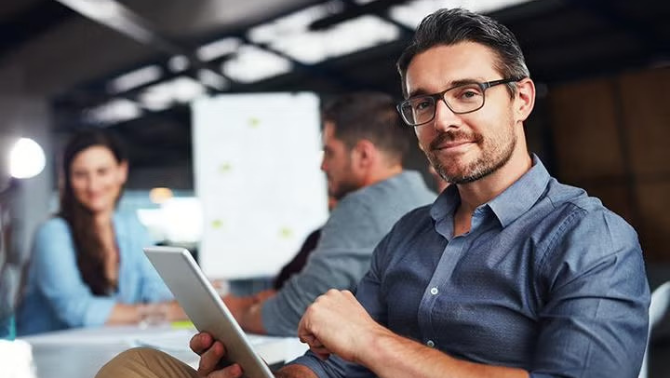 Man holding tablet while sitting in the office representing how to maximise savings with corporate travel discounts.