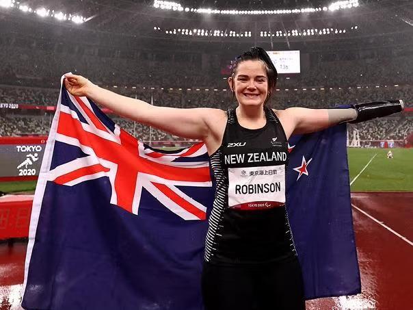 An athlete holding the New Zealand flag demonstrating how for Kiwi businesses prioritising corporate travel sustainability, there’s a lot to learn from how Paris is planning and executing this global event.