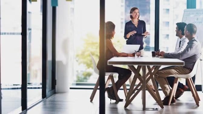A group of co-workers in a team meeting demonstrating the benefits of packing light for business trips. 