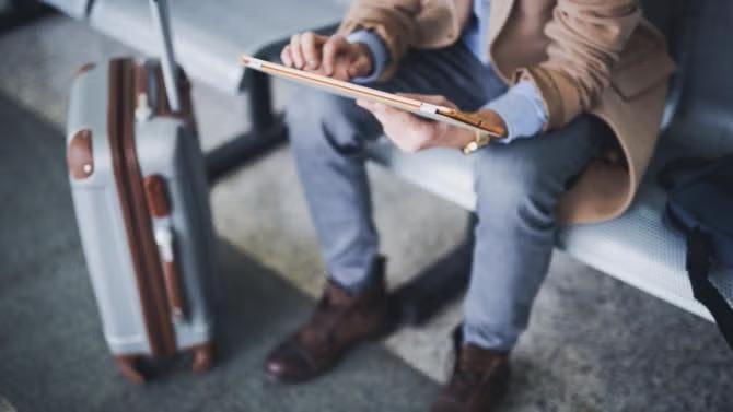 A man working on an iPad with a small suitcase demonstrating the benefits of packing light for business trips.