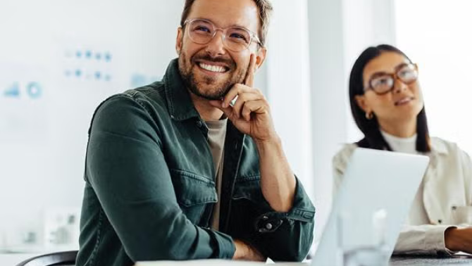 A man and woman sitting in the office looking at presentation demonstrating the importance of building travel programs aligned with your ESG objectives.
