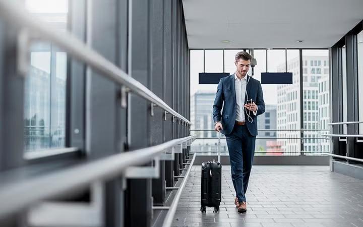 A man walking through the airport with a suitcase demonstrating the benefits of unpacking the basics of business travel.