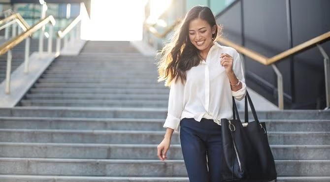 Smiling woman walking down the stairs  demonstrating the importance of choosing the best insurance with a travel expert.