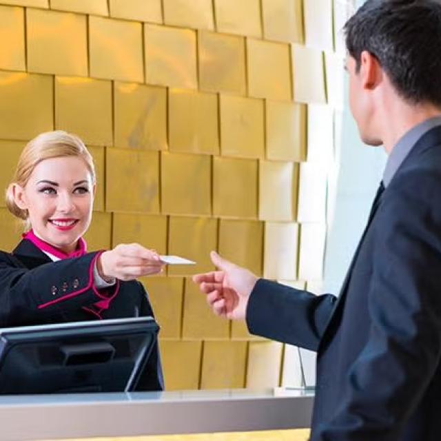 Hotel staff handing over keycard to guest demonstrating how Corporate Traveller makes the job of designing a travel policy easy with its unique automated online travel policy tool