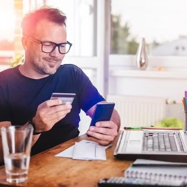 Man holding credit card and smartphone demonstrating the importance of understanding credit card insurance.
