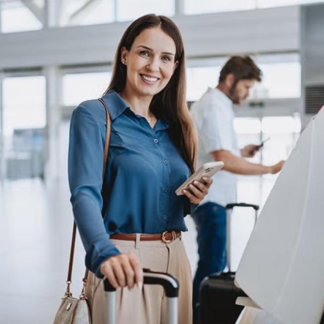 A woman standing at the check-in counter at the airport representing the State of the Market* Survey for Flight Centre Corporate has revealed that 40 per cent of businesses plan to increase their travel in FY25 (July to June).