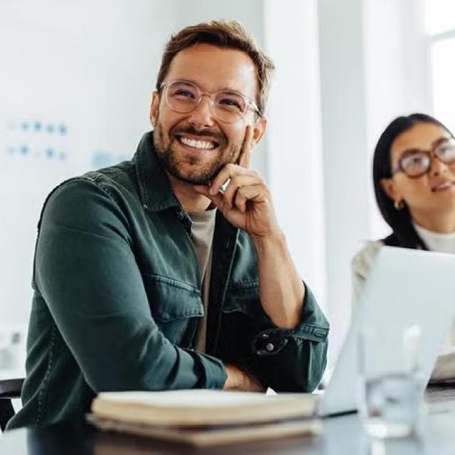 A man and woman sitting in the office looking at presentation demonstrating the importance of building travel programs aligned with your ESG objectives.