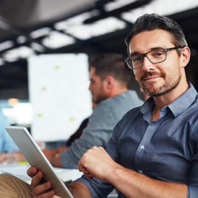 Man holding a tablet in the office how to leverage corporate travel discounts to maximise your savings.